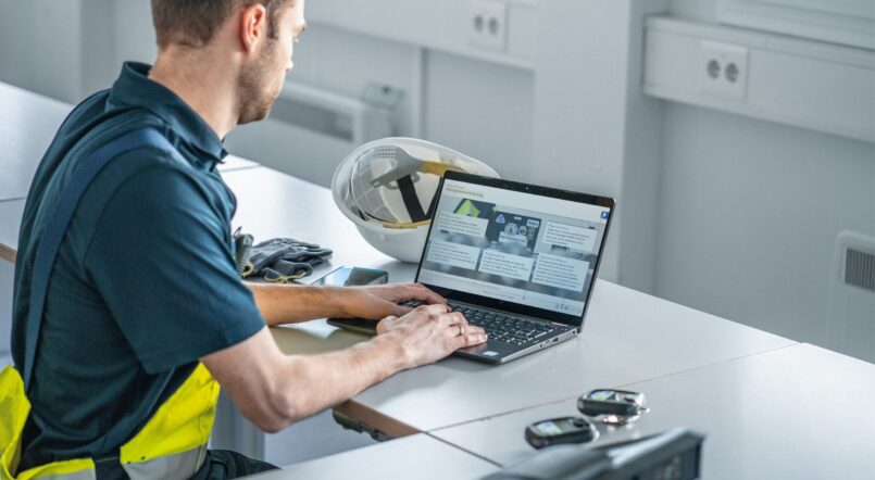 Mann sitzt mit Laptop am Arbeitsplatz.