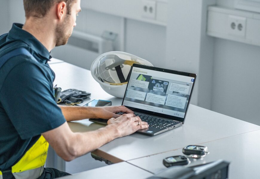 Mann sitzt mit Laptop am Arbeitsplatz.